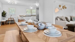 Una cucina moderna con mobili bianchi, un tavolo da pranzo apparecchiato con piatti e ciotole bianche e una panca in legno.