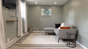 A modern living room with a grey sofa, a small round table, and a painting on the wall.