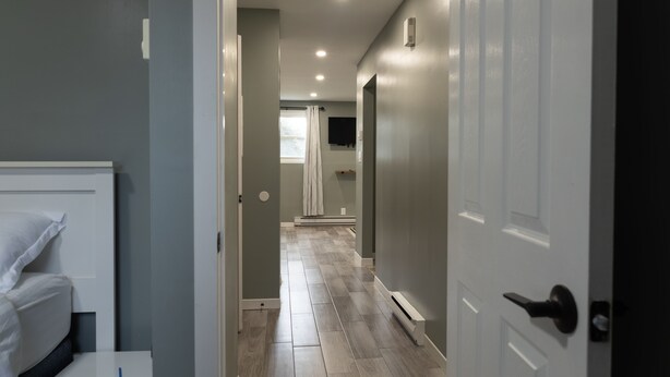A hallway with a bed, a door, and a window.