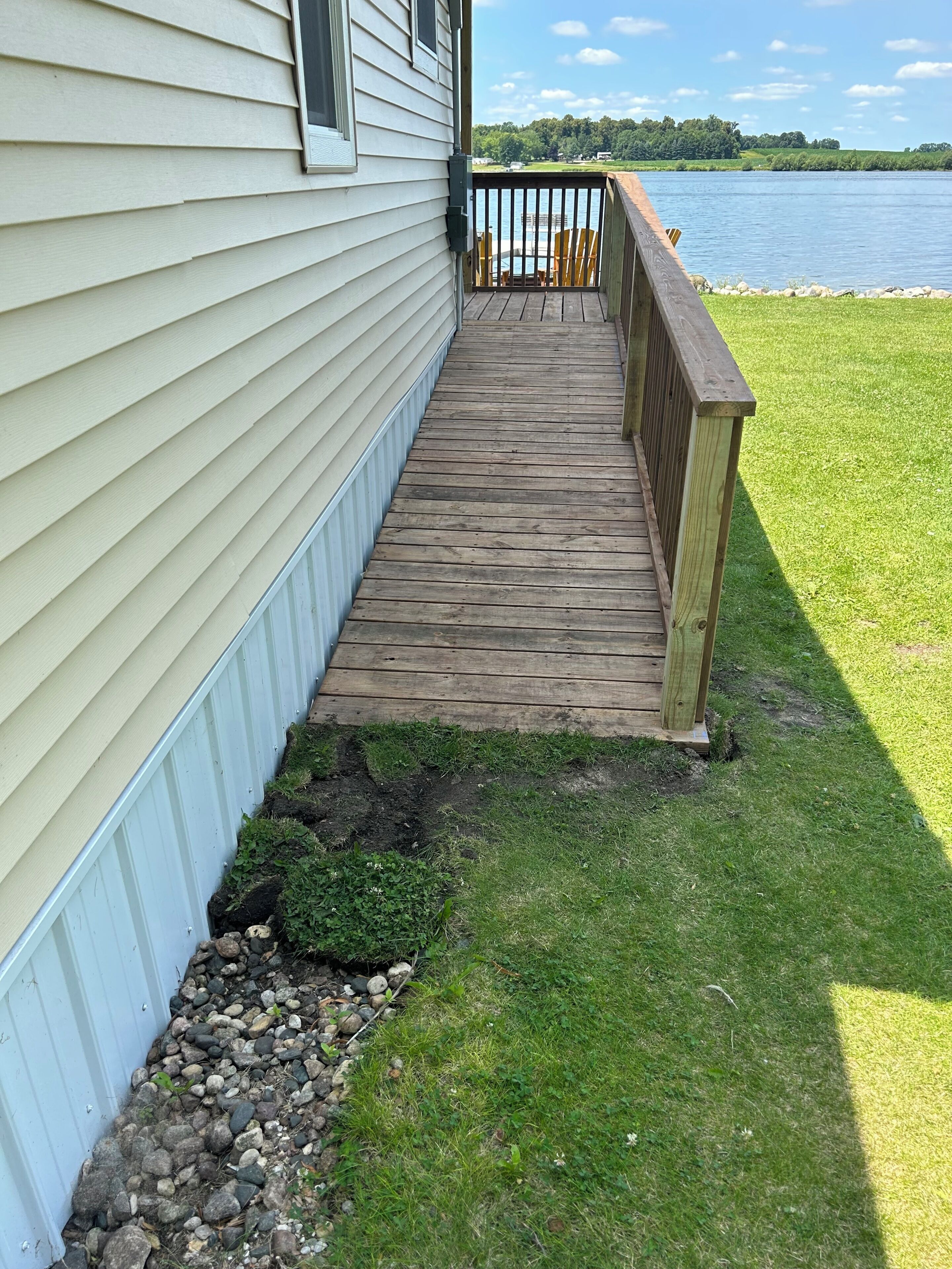 Une terrasse en bois qui mène à une maison offrant une vue sur un lac.