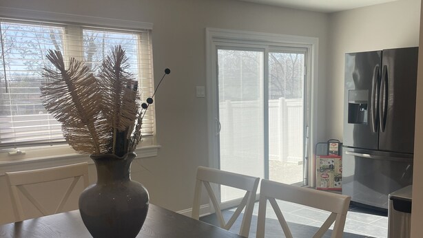 A dining area with a dark wooden table, white chairs, and a vase with dried plants.