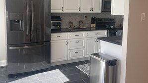 A modern kitchen with white cabinets, stainless steel appliances, and a black tiled floor.