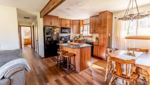 A spacious kitchen with wooden cabinets, a central island, bar stools, and a dining table with chairs. - The Bartlett Nook/ HOT TUB/ 3-BEDROOM/ 4 BEDS/ CLOSE TO LU (Lynchburg)