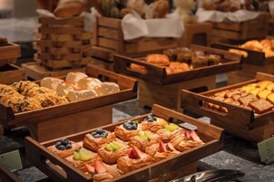 A variety of baked goods displayed in wooden trays, including pastries, bread, and desserts.