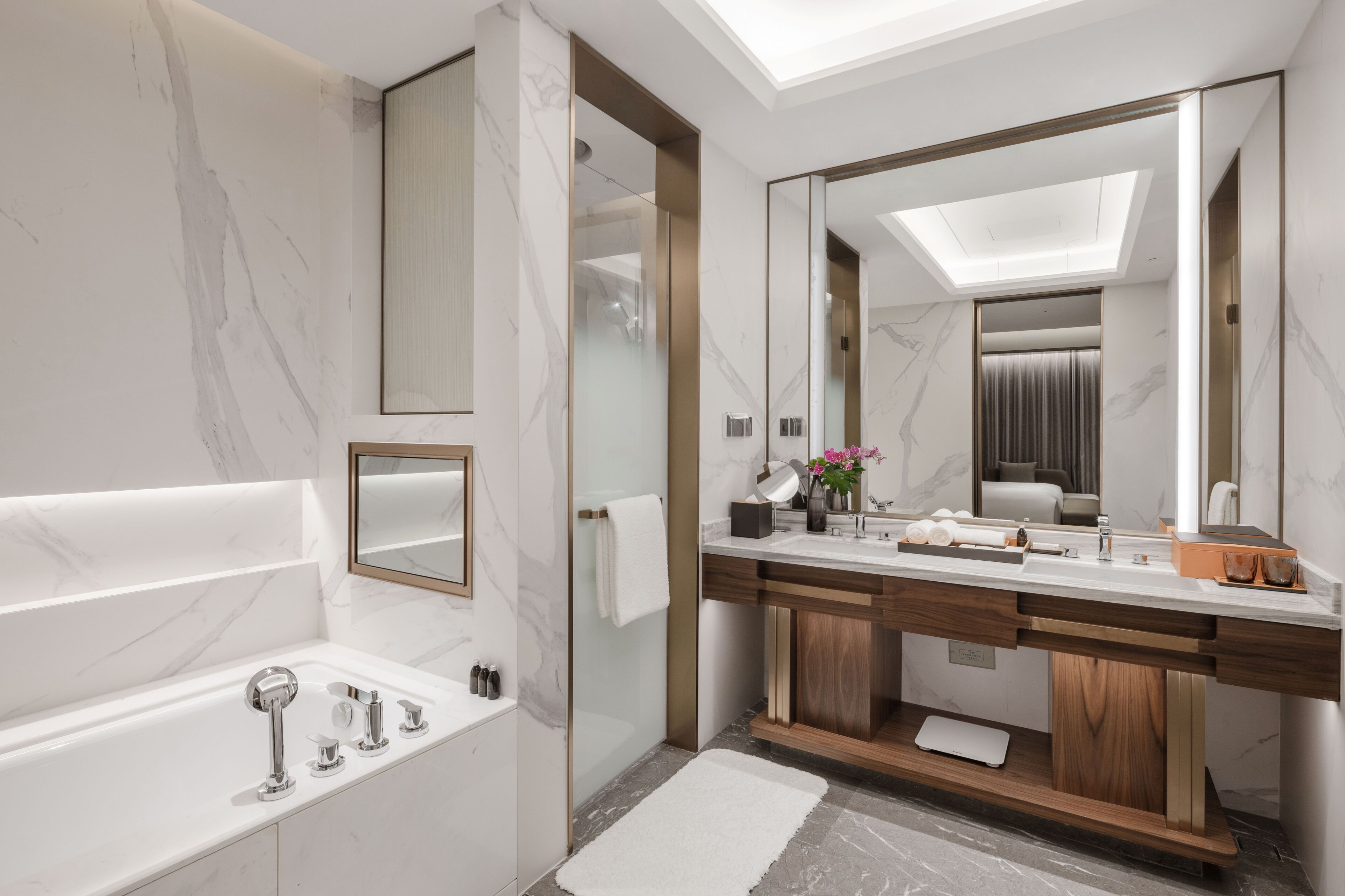 Une salle de bain moderne dotée d’un grand miroir, d’une baignoire, d’un meuble-lavabo et d’un espace douche.