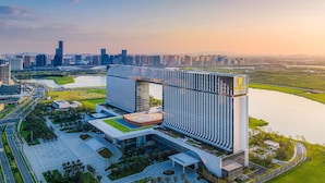 A modern hotel with a central courtyard, surrounded by greenery and a body of water. - Suzhou International Conference Hotel (Suzhou)