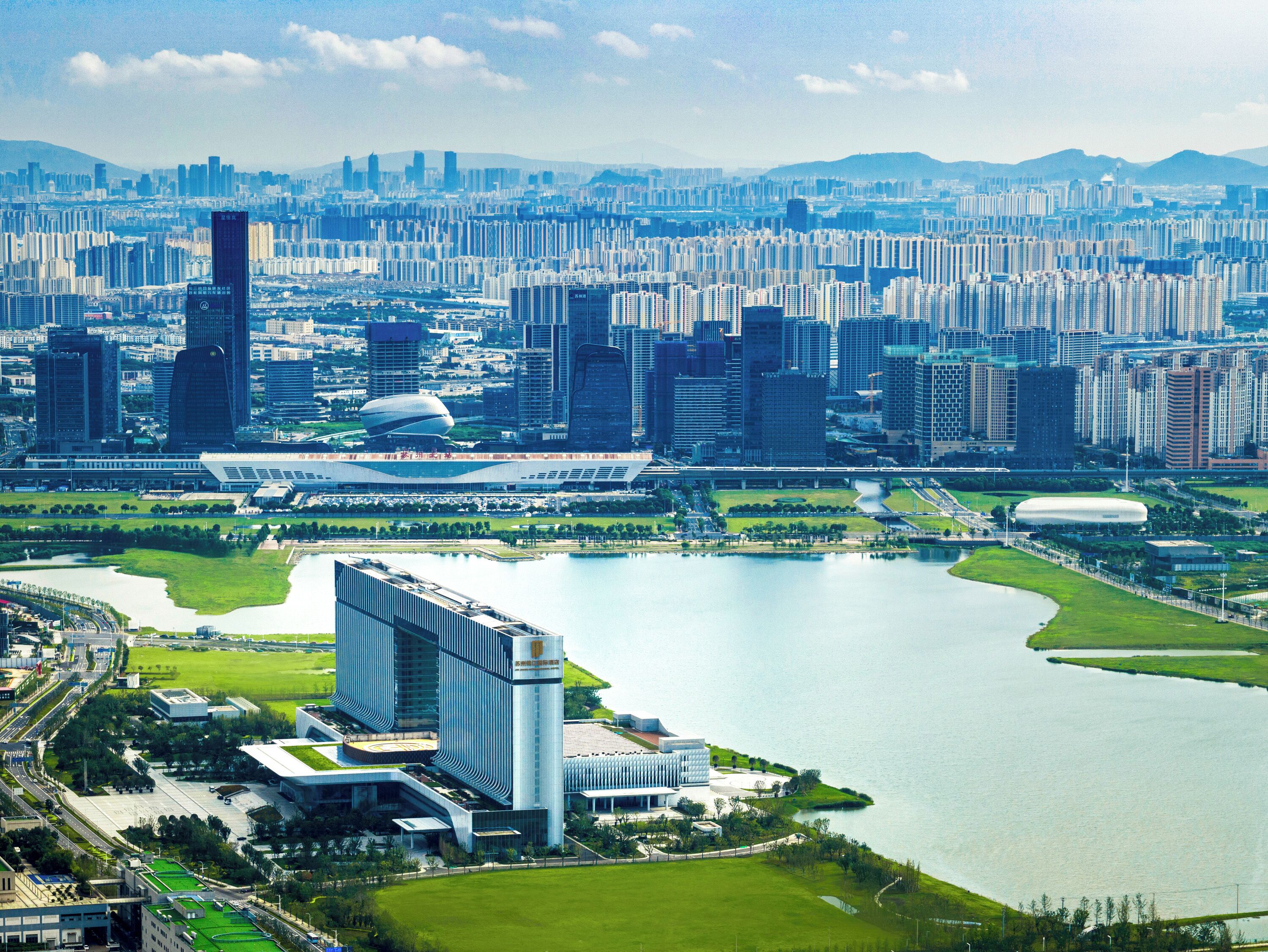 A cityscape with high-rise buildings, a large body of water, and a distinctive modern building with a curved roof.