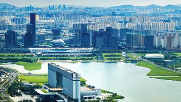 A cityscape with high-rise buildings, a large body of water, and a distinctive modern building with a curved roof.