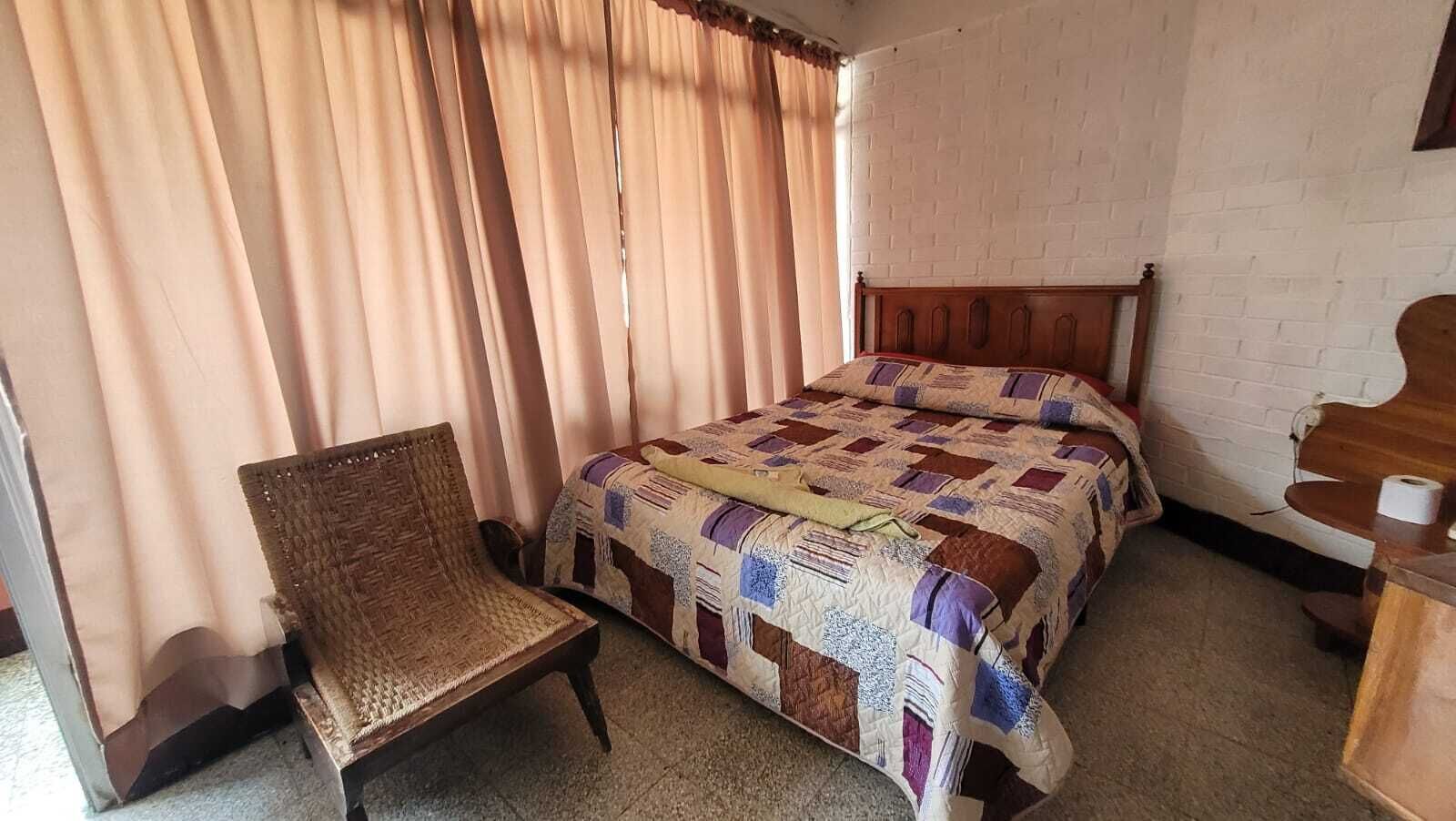 A room with a bed, a chair, and a wooden dresser.
