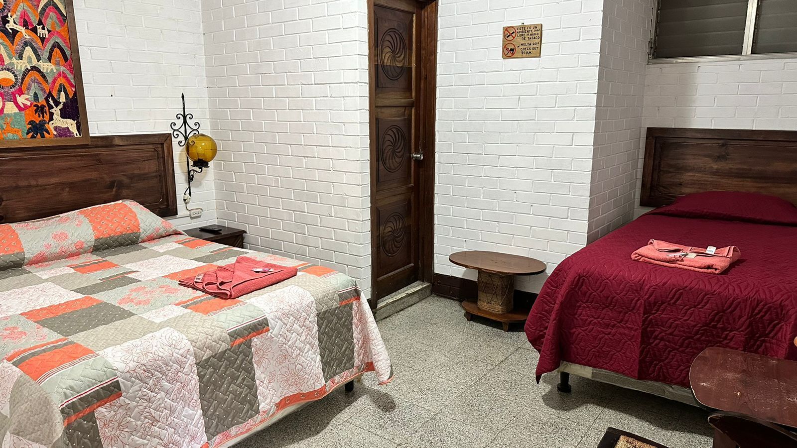 A room with two beds, a small round table, and a door.