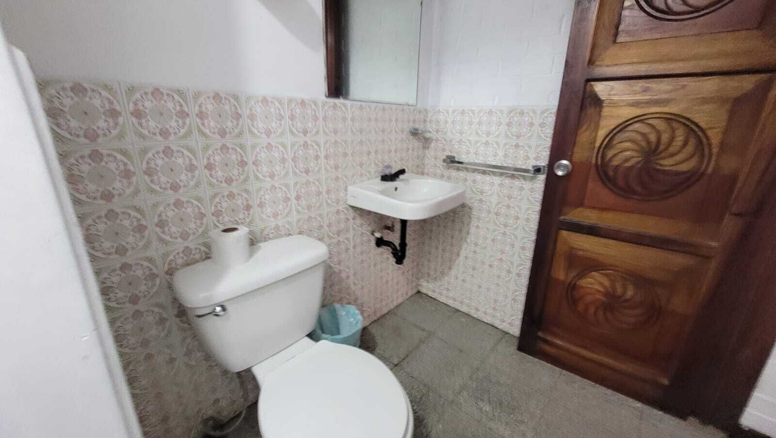 A small bathroom with a toilet, sink, and a wooden door.