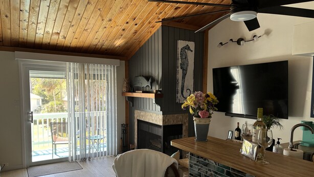 Uma sala de estar acolhedora com lareira, televisão na parede e um espaço de jantar com mesa e cadeiras de madeira.