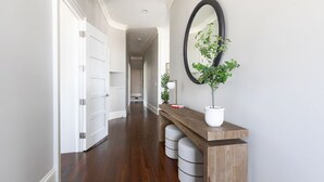 A hallway with a wooden console table, a potted plant, and a mirror on the wall. - Historic Charleston meets Modern luxury  (Charleston)