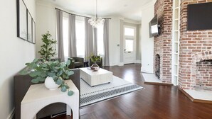A modern living room with a fireplace, a sofa, a coffee table, and a large window with curtains. - Historic Charleston meets Modern luxury  (Charleston)