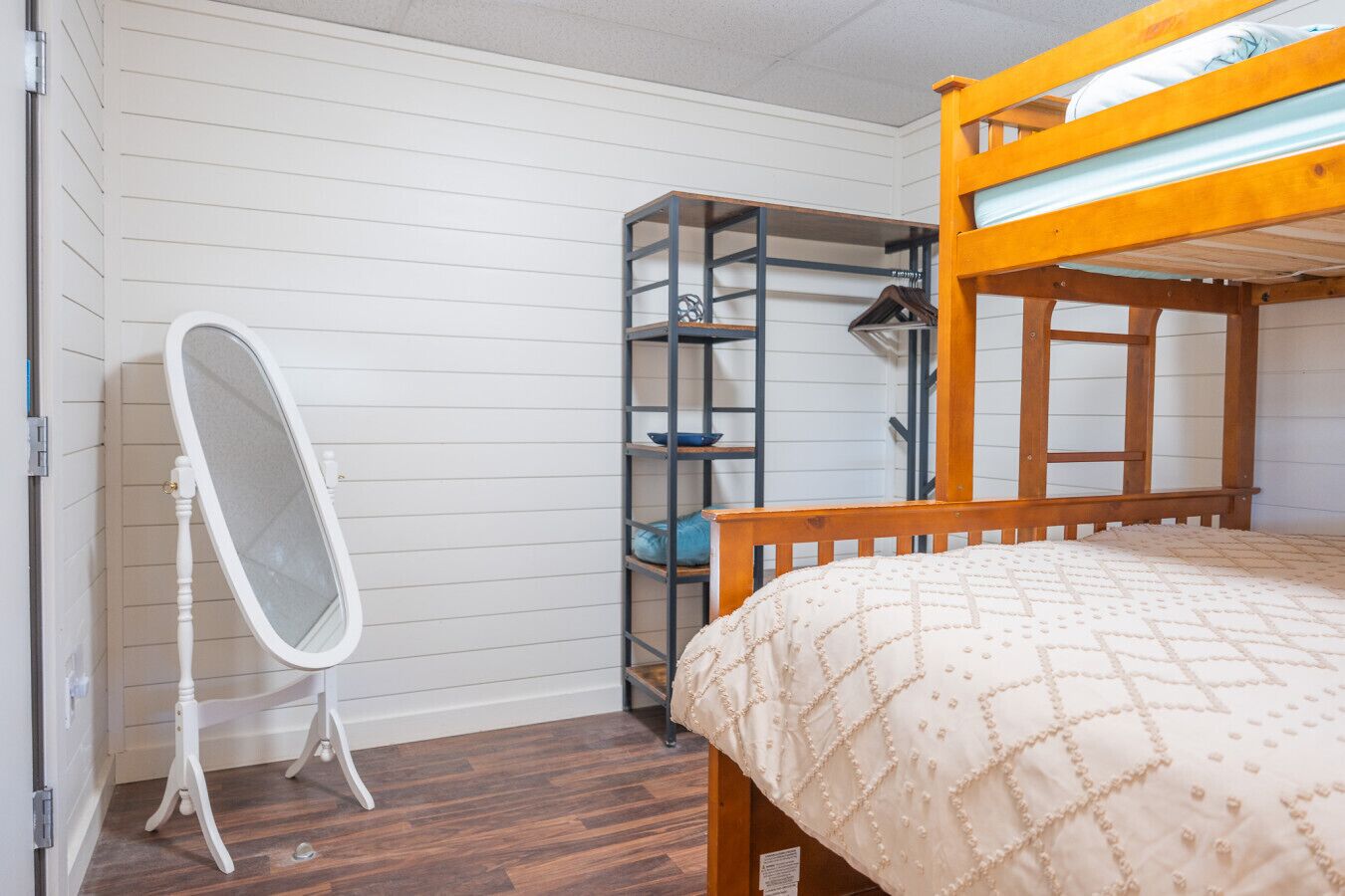 Una habitación pequeña con una cama litera, un espejo y una estantería.