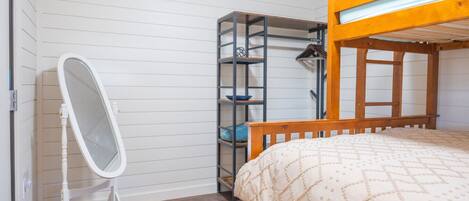 Una habitación pequeña con una cama litera, un espejo y una estantería.