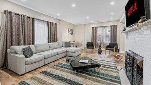 Una sala de estar moderna con un sofá modular, una mesa de centro, una chimenea y un televisor montado en la pared.