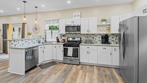 Una cocina moderna con armarios blancos, electrodomésticos de acero inoxidable y salpicadero de azulejos.