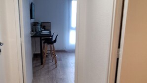 A narrow hallway with wooden flooring leading to a dining area with a table and chairs. - Studio Cosy le Natureavec Parking Fermé (Lourdes)