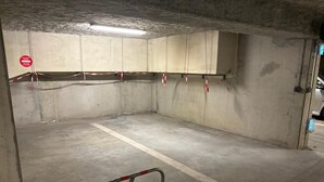 A parking garage with concrete walls, a metal barrier, and a red and white caution tape. - Studio Cosy le Natureavec Parking Fermé (Lourdes)