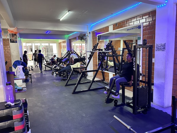 Un gimnasio con diverso equipo de ejercicio, incluyendo bancos y máquinas de pesas.