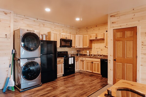 A compact kitchen with wooden cabinets, a microwave, a double-door refrigerator, and a washing machine.