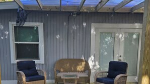 A covered outdoor deck with wicker furniture and a small table.