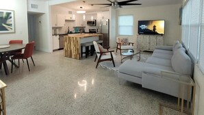 A spacious living area with a kitchen, dining area, and a large sofa.