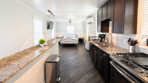 A modern kitchen with dark wood cabinets, granite countertops, and stainless steel appliances. - Florida Room: Walk DNTN | Studio | Lux Bath | Pet Welcome (Gainesville)