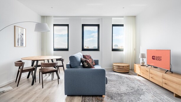 A modern living room with a sofa, a dining table with chairs, a TV, and large windows. - GuestReady - A lovely vacation in Matosinhos (Matosinhos)