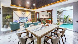A modern living room with a pool, a dining area, and a view of the pool. - Villa Rumpi Seminyak by Nagisa Bali (Legian)