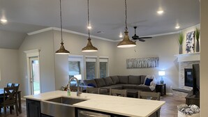 A modern kitchen with a large island, dark cabinetry, and stainless steel appliances.