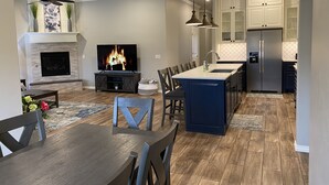 A modern kitchen with a central island, built-in appliances, and a dining area with a fireplace.