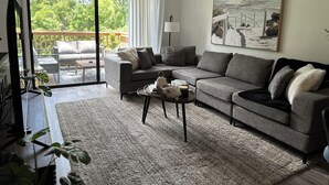 Ein Wohnzimmer mit grauem Sofa, einem Couchtisch und einem Gemälde einer verschneiten Landschaft.