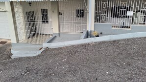 A residential building with a gated entrance, a covered porch, and a small garden area. - Beautiful 2-Bed Apartment in Montego Bay (Montego Bay)