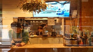Un café avec un comptoir en bois, un écran de télévision au-dessus et divers appareils pour préparer le café.
