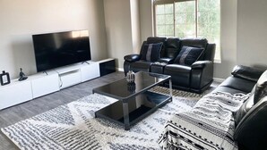 Ein modernes Wohnzimmer mit Flachbildfernseher, Ledersofa und einem großen Rundbogenfenster.