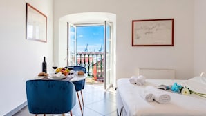 A hotel room with a bed, a dining table with chairs, a balcony with a view of cranes, and framed artwork on the walls. - Sea View Apartment Next To Acquarium, Genova, Italy (Genova)