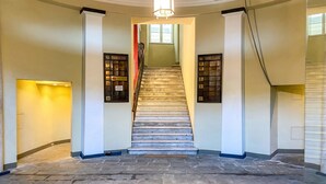 A grand staircase with a chandelier, a red accent wall, and a series of numbered doors. - Sea View Apartment Next To Acquarium, Genova, Italy (Genova)