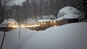 Un espace extérieur enneigé, doté d’une structure en forme de dôme et d’un bâtiment dont le toit est recouvert de neige.