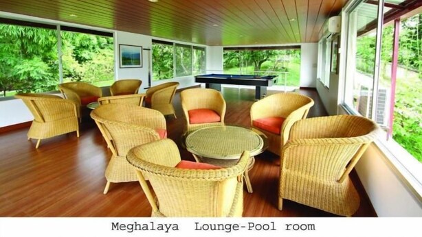 A lounge with wicker furniture, a pool table, and large windows offering a view of greenery. - Nazimgarh Garden Resort (Sylhet)