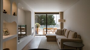 A modern living room with a flat-screen TV, a sofa, a small table, and a dining area with a table and chairs. - Villa located in "Douro Verde" with outdoor pool, 5 minutes from the Douro River (Paços de Gaiolo)
