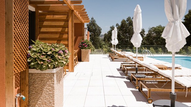 A poolside area with sun loungers and umbrellas, a wooden pergola, and a view of the pool. - Villa located in "Douro Verde" with outdoor pool, 5 minutes from the Douro River (Paços de Gaiolo)