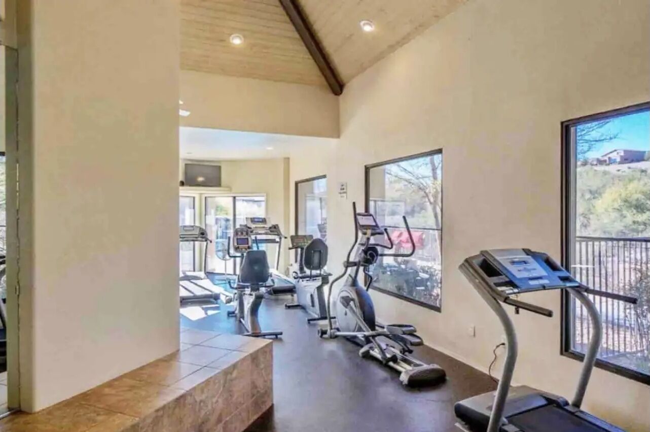 Un gimnasio con cintas de correr, bicicletas estáticas y máquinas de pesas.