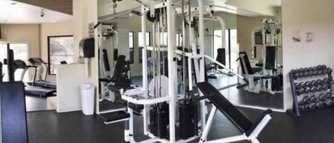 A gym with exercise equipment, mirrors, and dumbbells.