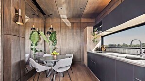 Une cuisine moderne avec une table à manger ronde, des chaises grises et une grande fenêtre.