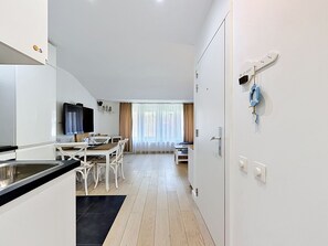 A modern kitchen with white cabinets, a black countertop, and a dining area with a table and chairs. - Centrally located "Key Point" by Interhome (Blankenberge)