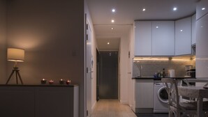 A modern kitchen with white cabinets, a washing machine, and a dining area with a table and chairs.