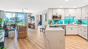 Een moderne keuken met witte kasten, een marmeren eiland en uitzicht op het groen.