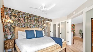 Een slaapkamer met een bed, een plafondventilator, een nachtkastje en een muur met een bloemmotief.